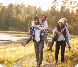 Family hiking piggybacking kids